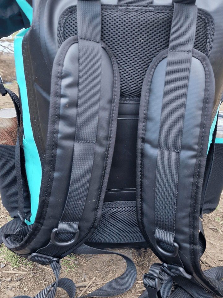 photo of the back of a mint green coloured waterproof bag, showing the padded area and the carrying straps