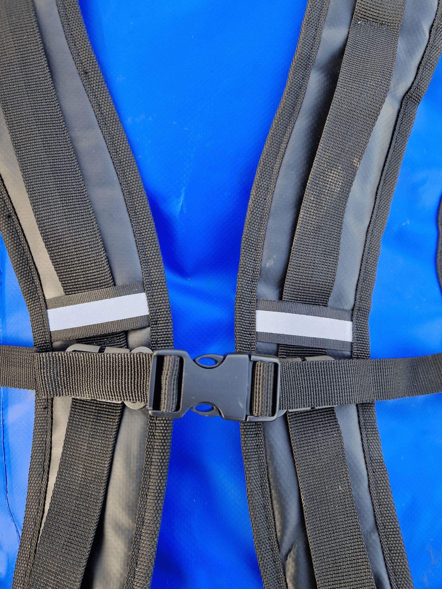 close up of the backpack straps and chest clip of the blue duffel bag