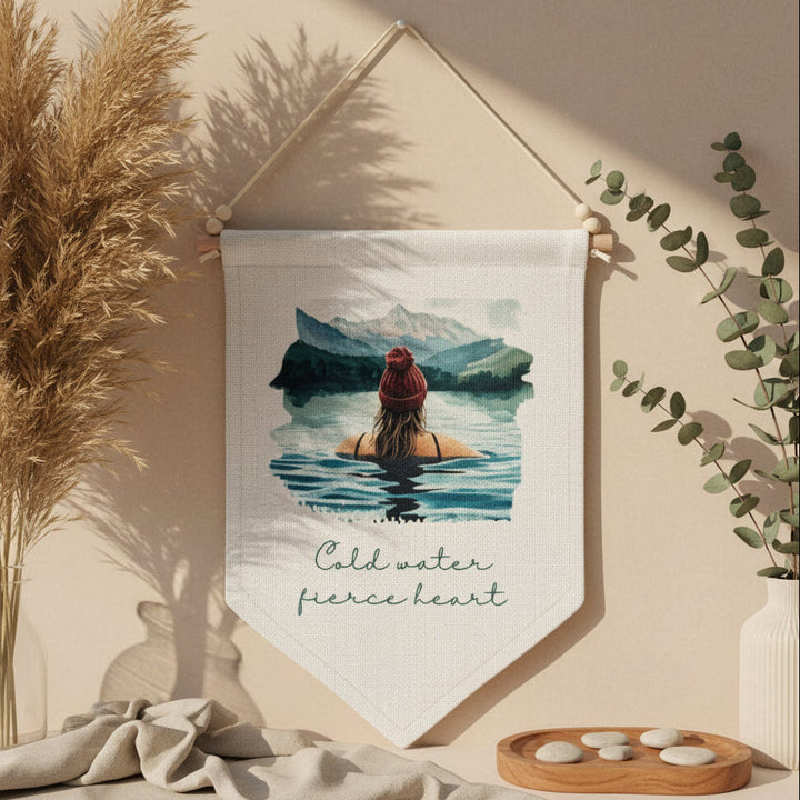 Fabric banner with a scenic design of a person in water and mountains, hanging on a beige wall.