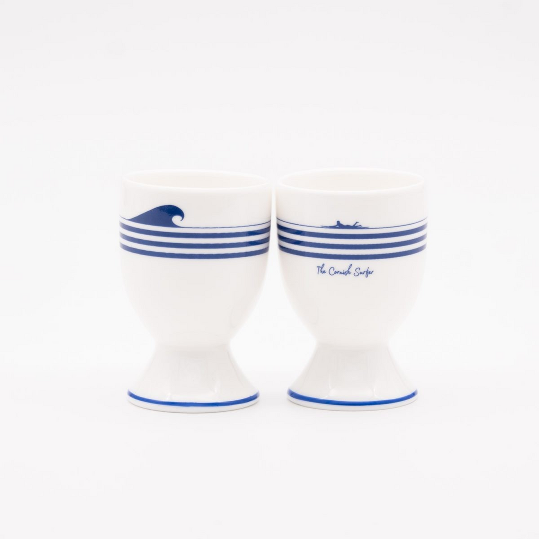 Two white ceramic egg cups with blue stripes and wave design on a white background