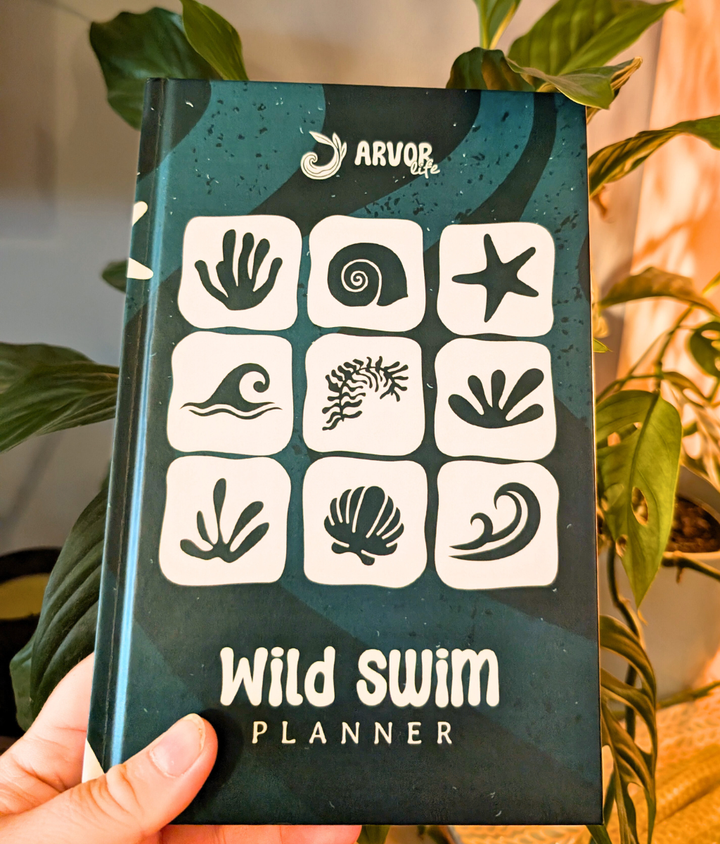 Hardback Wild Swim Planner open to weekly swim planning pages for wild swimmers.