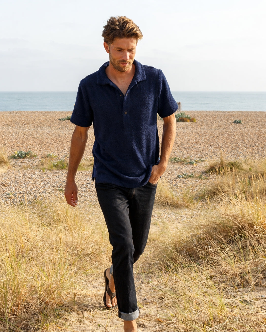 Navy Bond polo shirt by So English, made in the UK, displayed on a model showcasing casual beachwear style.