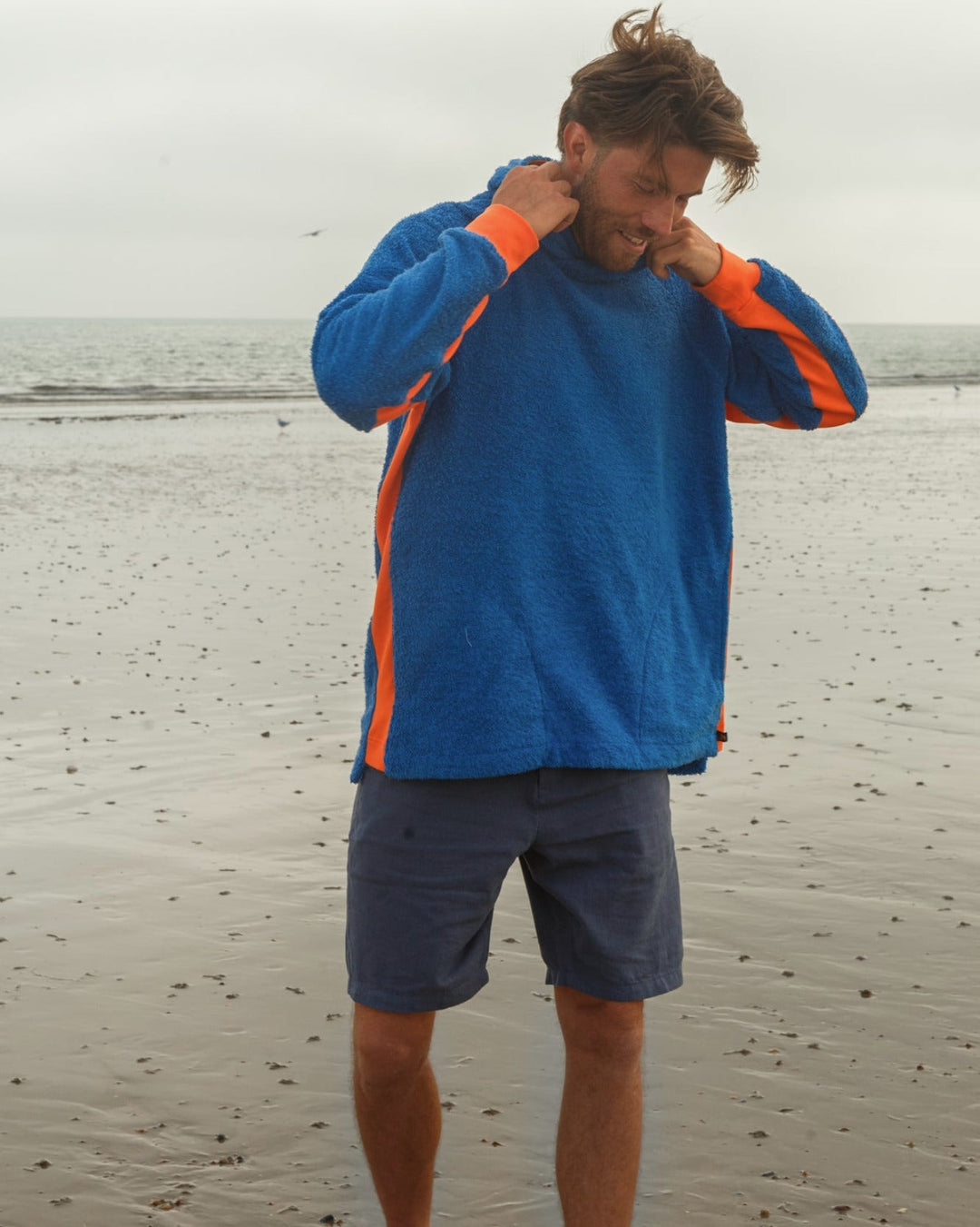 Bright blue and orange So English Hampstead hoodie with beachwear style, made in the UK, displayed on a model.