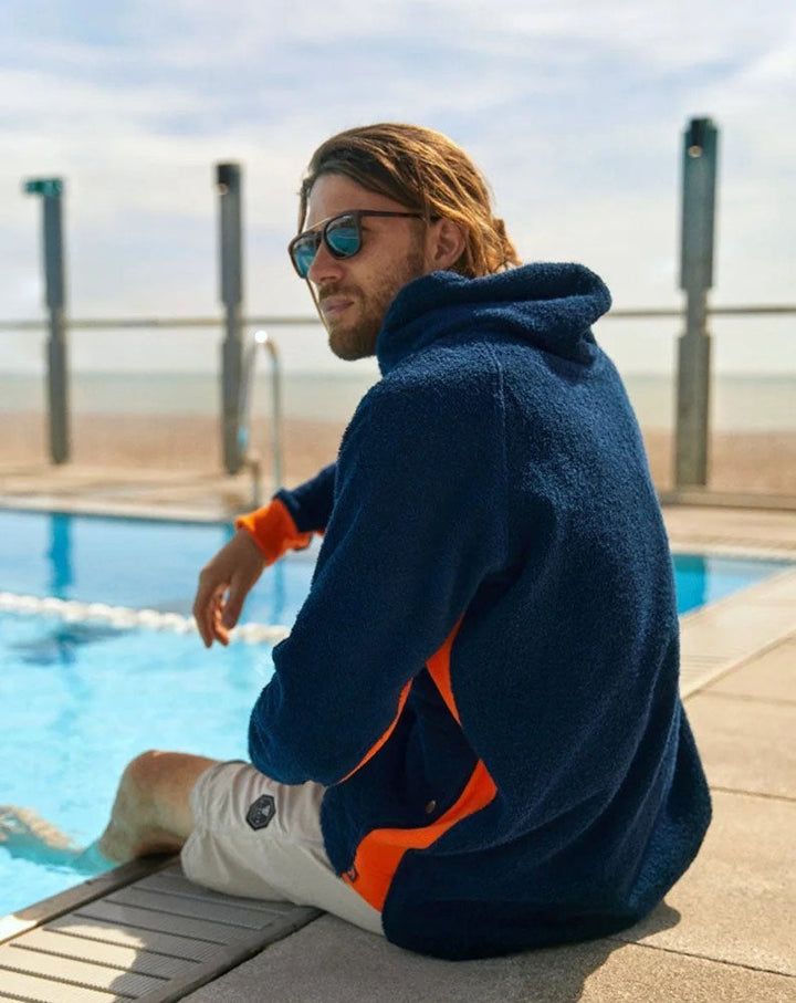 So English Hampstead navy and orange hoodie displayed outdoors, showcasing casual style and vibrant color contrast.