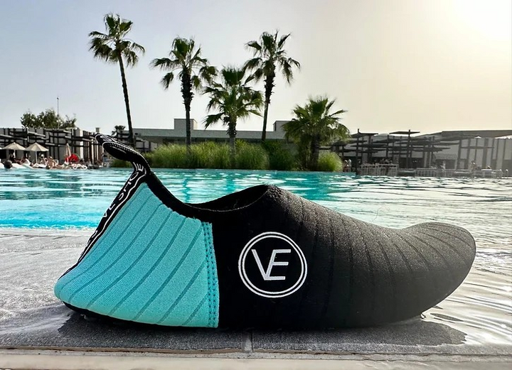 Image of the recyclable VE Shoe adult water shoes with black and aqua upper and black sole, featuring a distinctive VE logo.