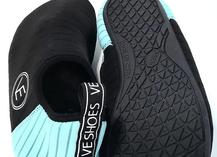 Flat shot of the sole of a pair of adult water shoes with black and aqua upper and black sole, featuring a distinctive VE logo.