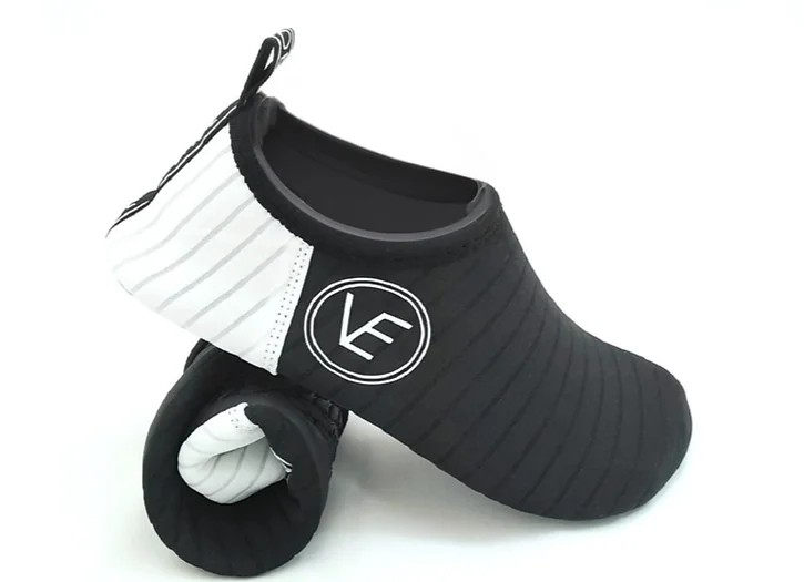 A pair of adult black and white recyclable water shoes and the VE Shoes logo on the side.