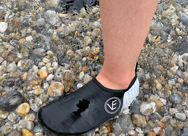 Black VE Shoe Water Shoes worn in the sea on a pebbly surface 
