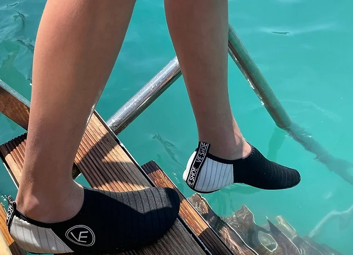 Image of VE Shoe's black water shoes stepping down a ladder into a pool