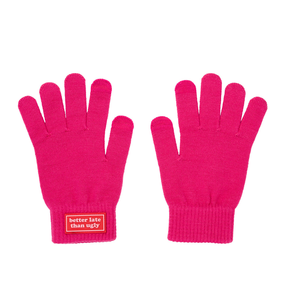 A flat shot of a pair of bright pink  gloves shown against a white background, with a red label on the cuff of the left glove that reads 'better late than ugly'.