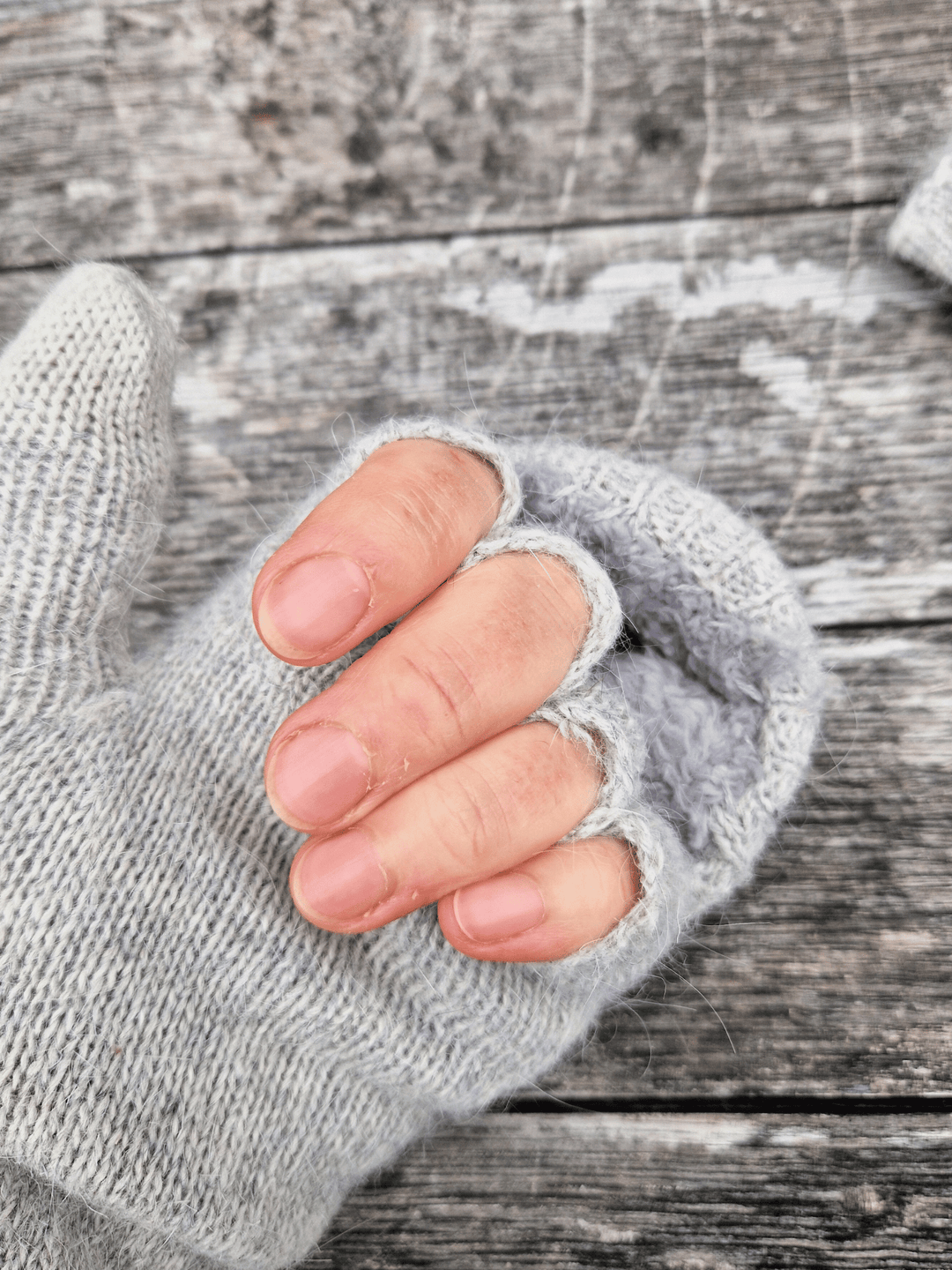 Close-up of a hand wearing a grey fingerless glove on a wooden surface