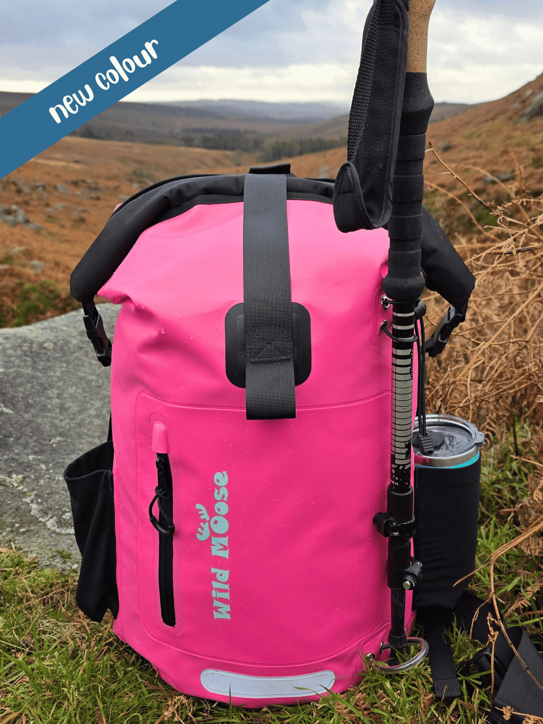 Pink backpack with hiking poles and a cup on a natural background