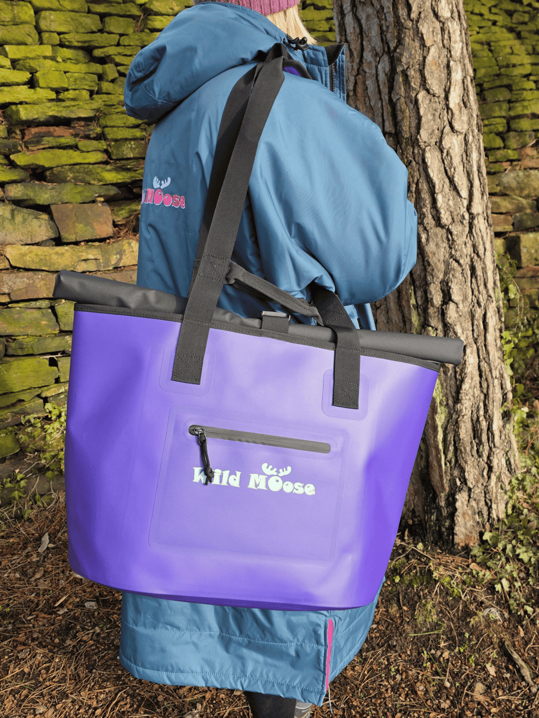 lady in blue robe with purple tote bag over shoulder stood next to a wall