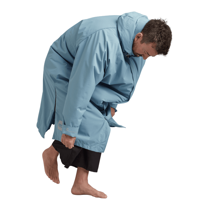 Side profile of a man changing underneath the Red Alter Evo long sleeve waterproof changing robe in Alpine Blue.