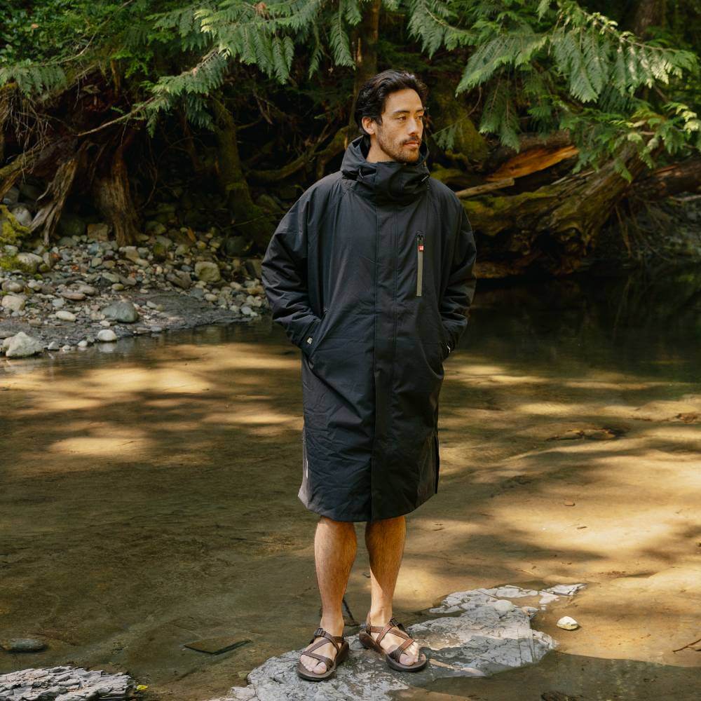 Male standing on a stone on a river's edge, wearing a Red Alter Evo long sleeve waterproof changing robe in Stealth Black.