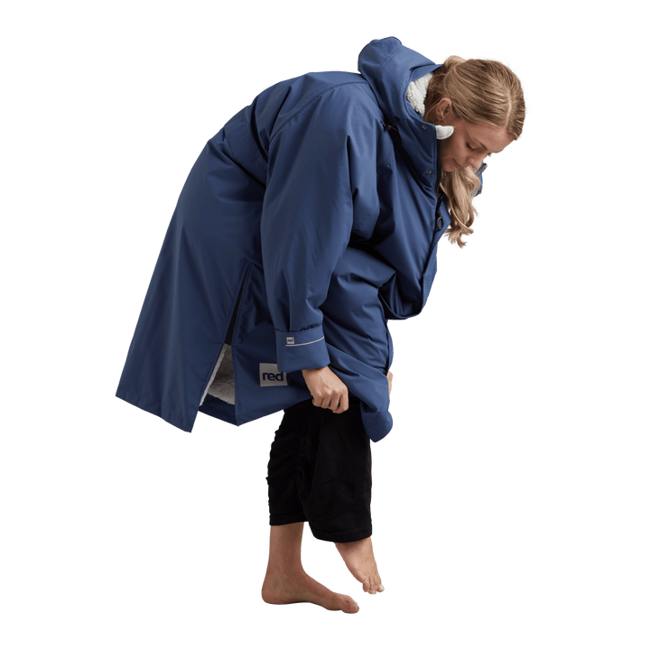 Side profile of a woman changing underneath the Red Alter Evo long sleeve waterproof changing robe in Admiral Blue.