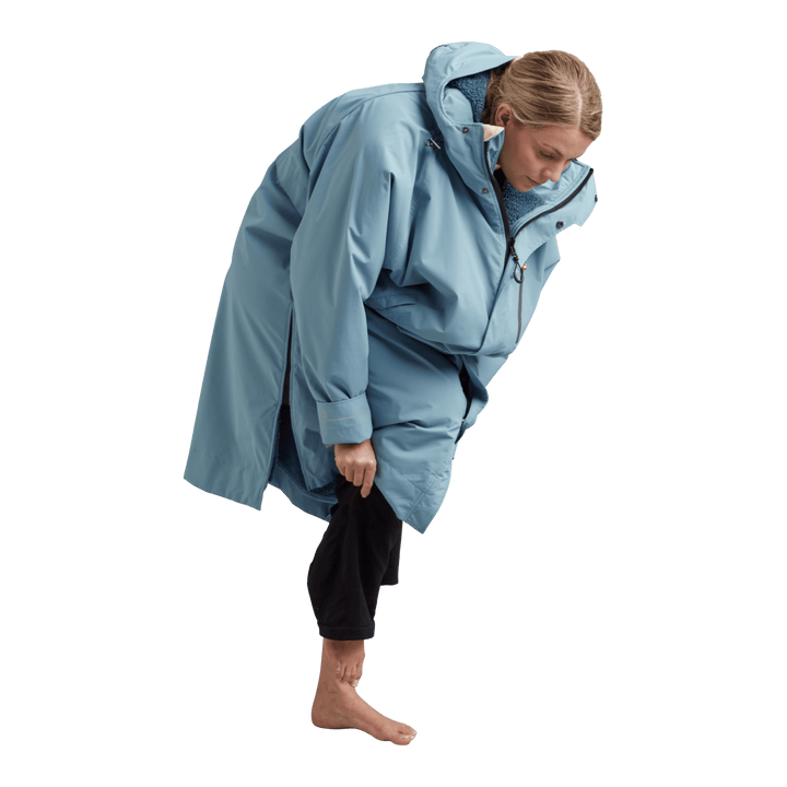 Side profile of a woman changing underneath the Red Alter Evo long sleeve waterproof changing robe in Alpine Blue.