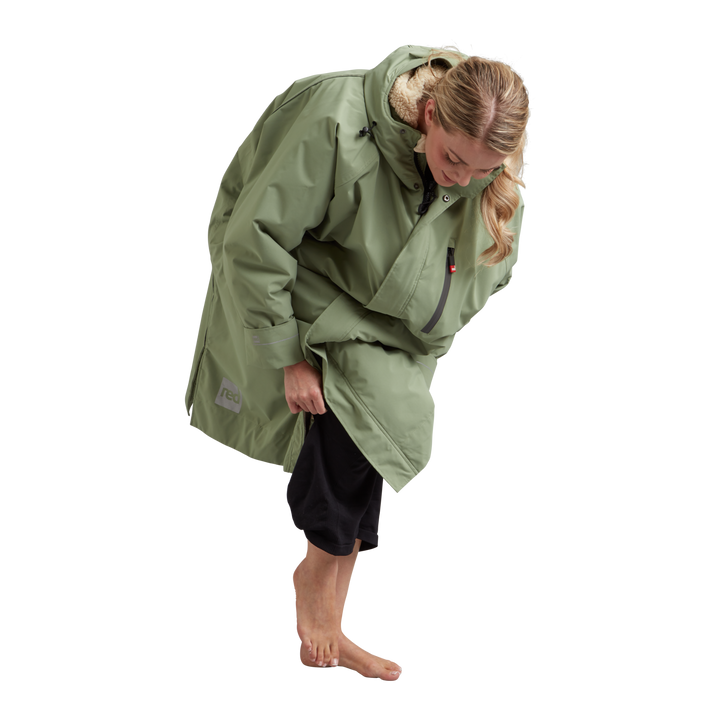 Side profile of a woman changing underneath the Red Alter Evo long sleeve waterproof changing robe in Sage Green.