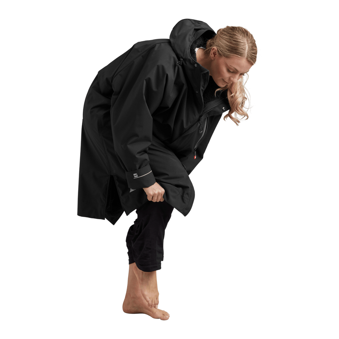 Side profile of a woman changing underneath the Red Alter Evo long sleeve waterproof changing robe in Stealth Black.