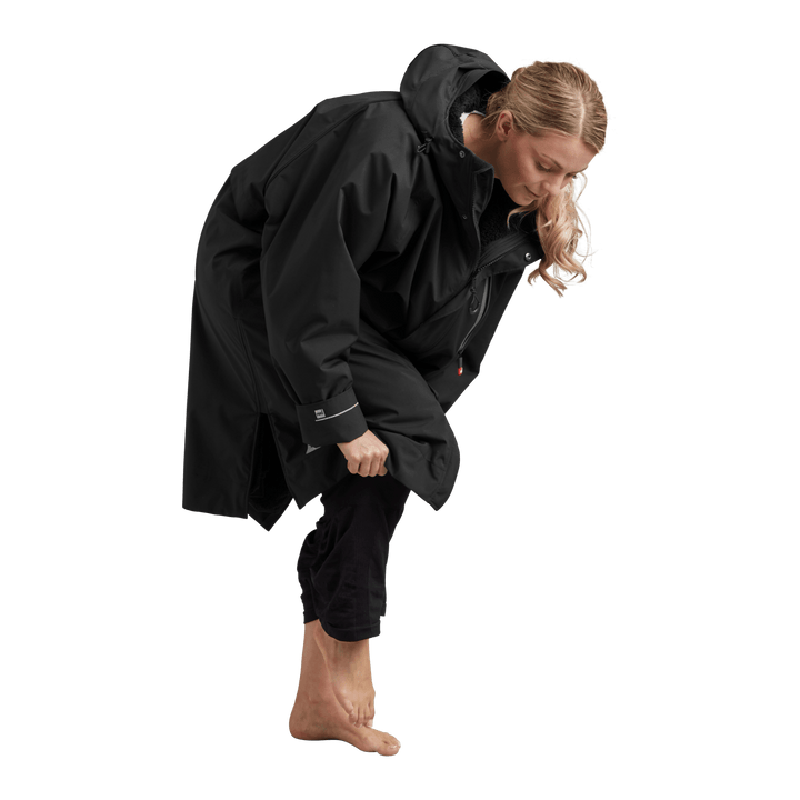 Side profile of a woman changing underneath the Red Alter Evo long sleeve waterproof changing robe in Stealth Black.