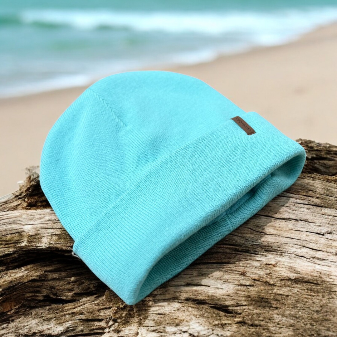 Peppermint Waterproof Beanie with discreet Swimbler logo tag, fleece lined and waterproof, photographed on the beach — Outdoor Swimmer Shop.