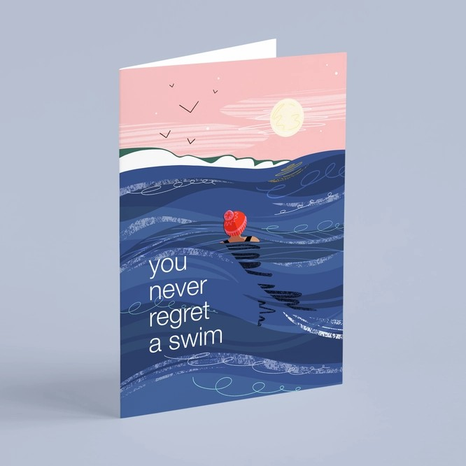 Greeting card with illustration of swimmer in bobble hat under the full moon, with text “You Never Regret a Swim.”